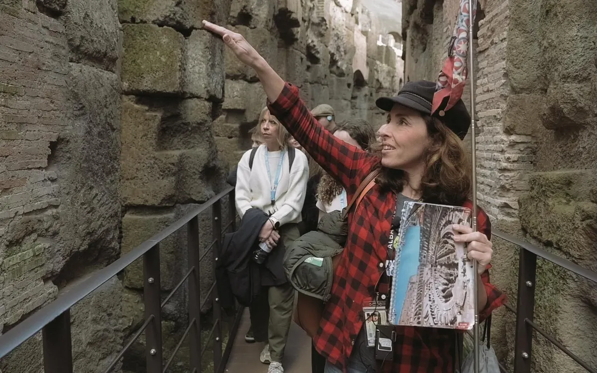 Ein Guide zeigt zwei Besuchern ein Detail im Colosseum